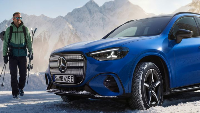 EIn blauer Mercedes in einer Winterlandschaft und ein Mann mit Ski Ausr�stung