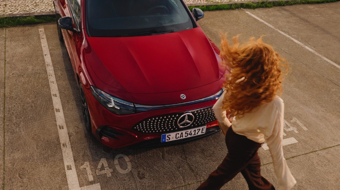 Ein geparkter roter Mercedes und eine Dame mit roten Haaren geht daran vorbei